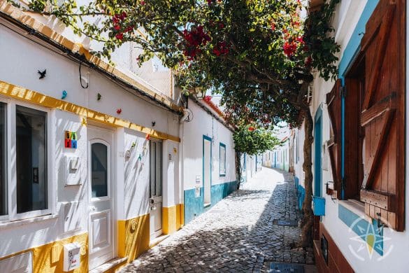 a street with white buildings and flowers in Ferragudo