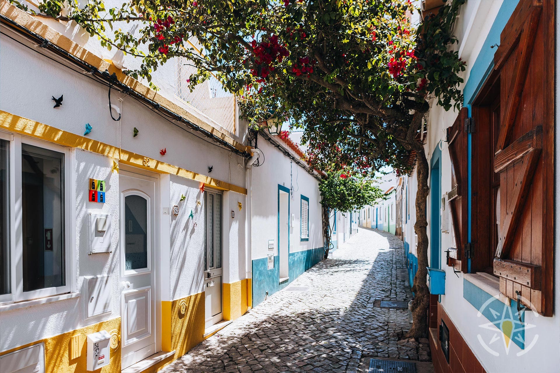 A Street With White Buildings And Flowers In Ferragudo